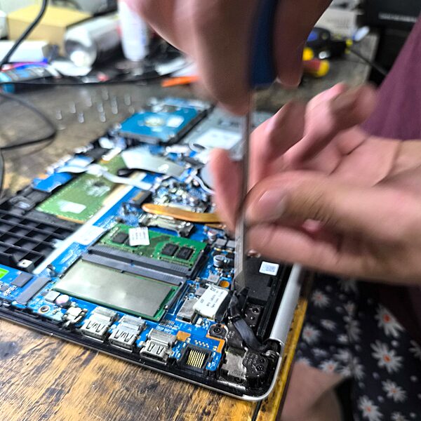 Reparación de notebook — manos con destornillador en motherboard